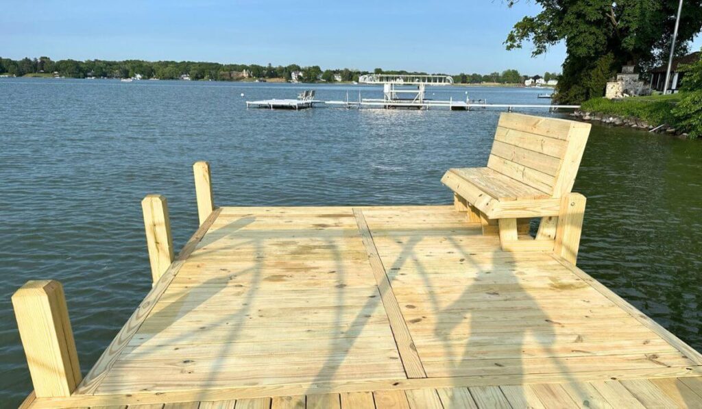 A wood dock with a large sunbathing platform and bench on Lac La Belle in Oconomowoc.