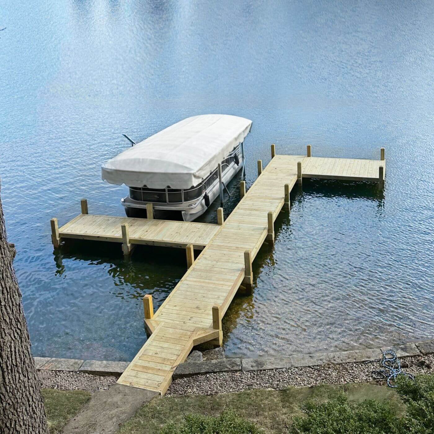 Custom Okauchee Lake dock built into the existing shoreline with angled access and boat slip